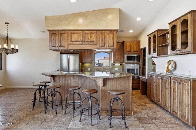 kitchen with stone countertops, baseboards, appliances with stainless steel finishes, a center island, and tasteful backsplash