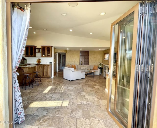 living room with lofted ceiling, stone finish floor, and recessed lighting