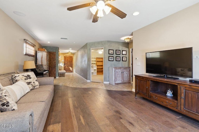 living room featuring a ceiling fan, baseboards, arched walkways, and wood finished floors