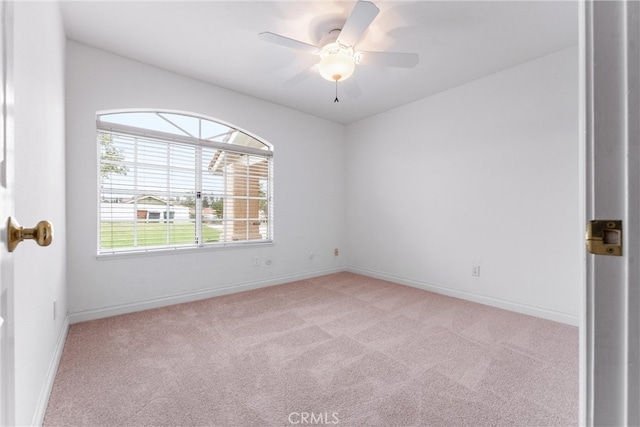 unfurnished room featuring light carpet, a ceiling fan, and baseboards