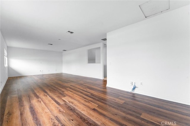 empty room with visible vents, wood finished floors, and attic access