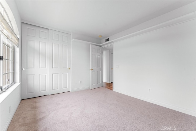 unfurnished bedroom featuring a closet, carpet flooring, visible vents, and baseboards