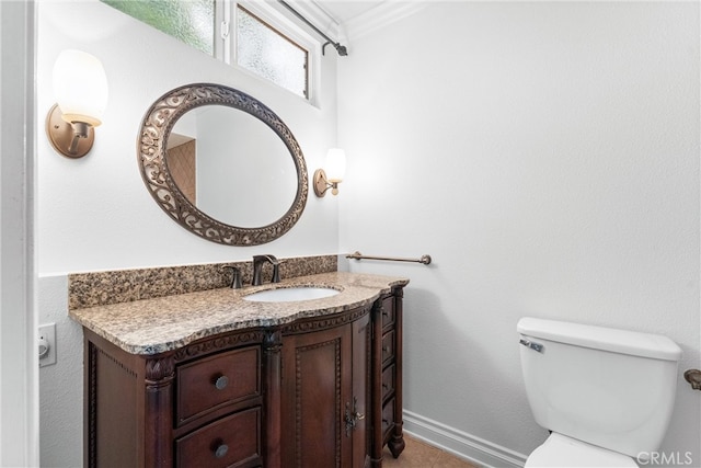 half bathroom with ornamental molding, baseboards, vanity, and toilet