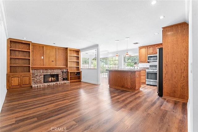 kitchen featuring a kitchen island, open floor plan, appliances with stainless steel finishes, a brick fireplace, and dark wood finished floors