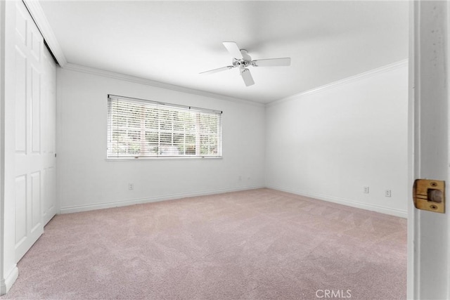 empty room with baseboards, ornamental molding, a ceiling fan, and light colored carpet