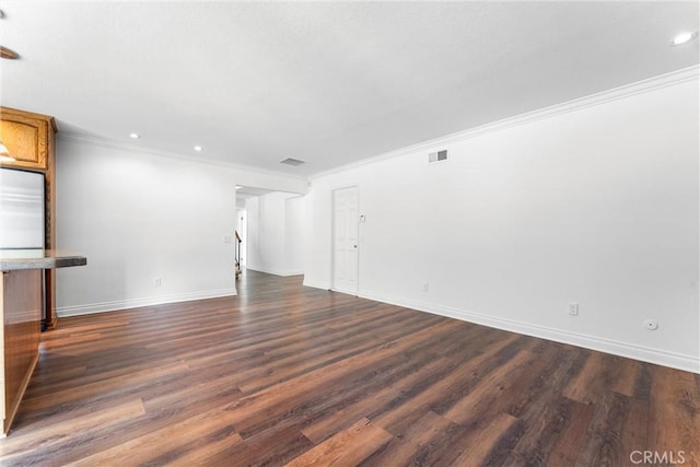 unfurnished room featuring dark wood-style floors, visible vents, ornamental molding, and baseboards