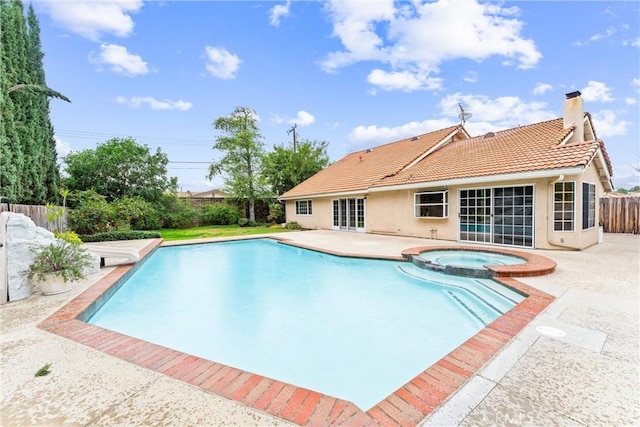 view of pool featuring a patio, fence, and a pool with connected hot tub