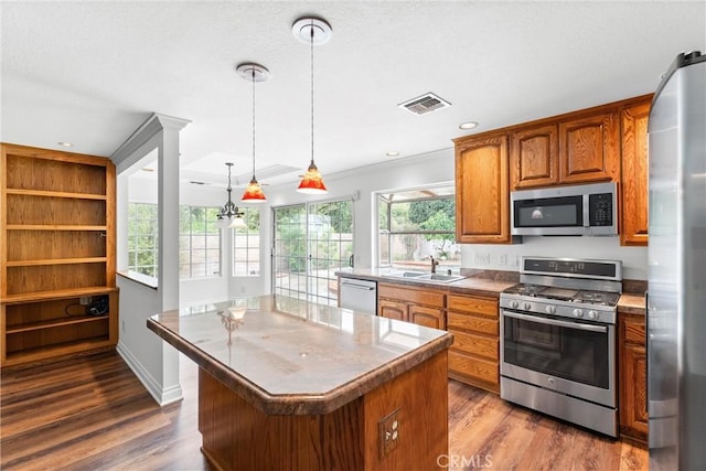 kitchen featuring appliances with stainless steel finishes, brown cabinets, visible vents, and dark wood-style flooring