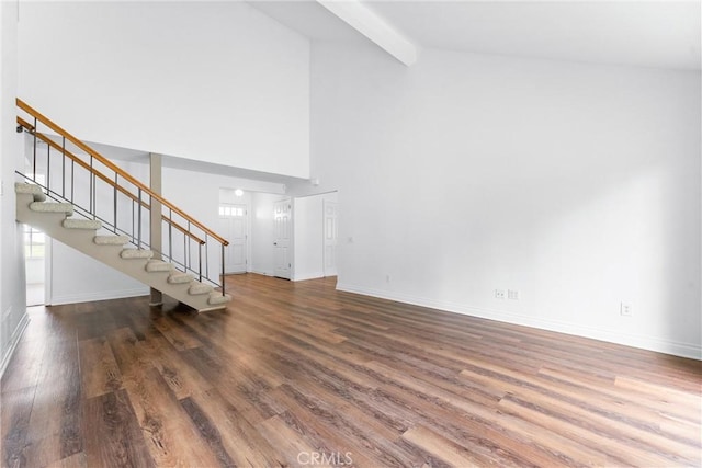 unfurnished living room featuring stairs, baseboards, wood finished floors, and beamed ceiling