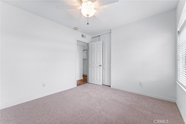 unfurnished bedroom with carpet floors, visible vents, baseboards, and a ceiling fan