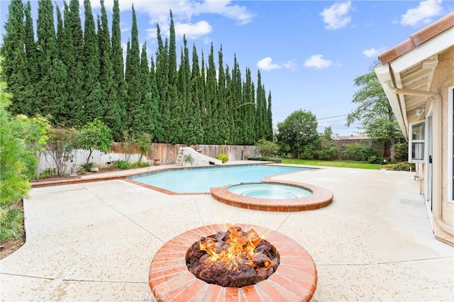 view of swimming pool featuring an outdoor fire pit, a pool with connected hot tub, a fenced backyard, and a patio