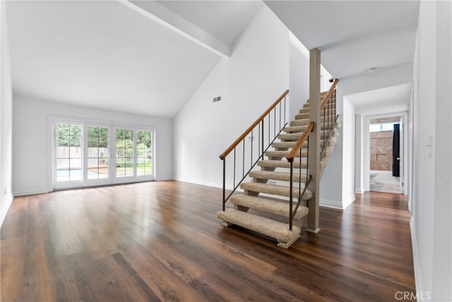 stairs with high vaulted ceiling, beam ceiling, visible vents, and wood finished floors