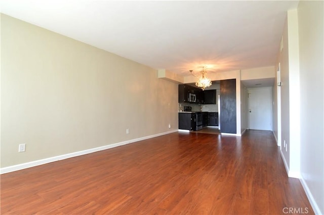 unfurnished living room with a chandelier, dark wood-style floors, and baseboards