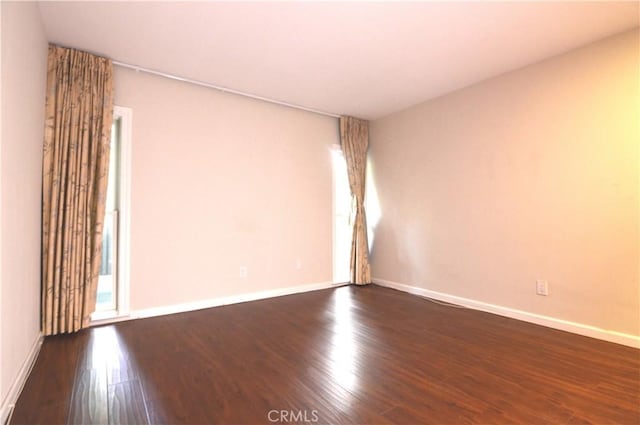 empty room featuring dark wood-style floors and baseboards