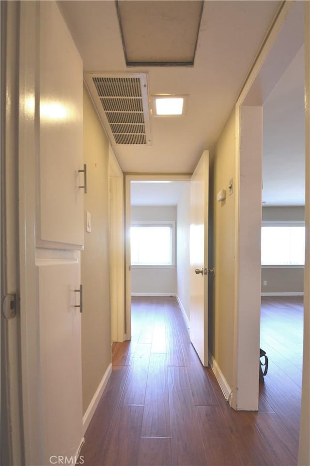 corridor featuring visible vents, dark wood finished floors, and baseboards