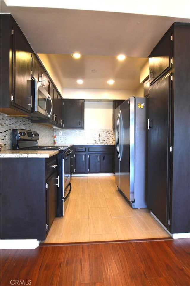 kitchen featuring a sink, stainless steel appliances, light wood-style floors, backsplash, and recessed lighting