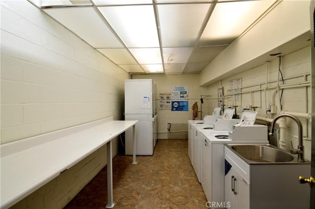 shared laundry area featuring concrete block wall, independent washer and dryer, a sink, and tile patterned floors