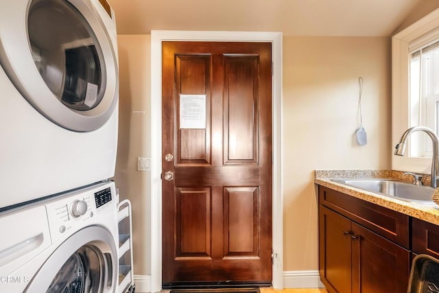 clothes washing area featuring stacked washing maching and dryer and a sink