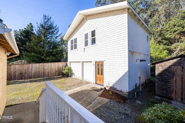 view of side of home with a garage and fence