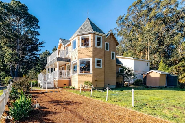 exterior space featuring a lawn, a balcony, crawl space, an outdoor structure, and a shed