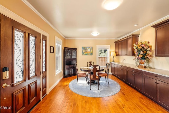 dining space featuring light wood-type flooring, baseboards, and ornamental molding