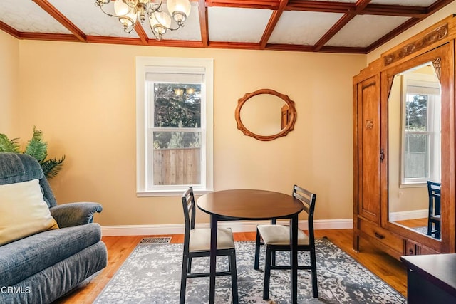 dining room with an inviting chandelier, coffered ceiling, baseboards, and wood finished floors