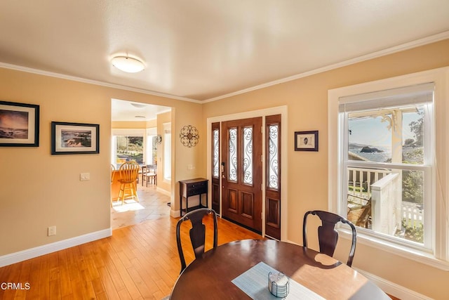 foyer entrance with light wood finished floors, baseboards, and ornamental molding