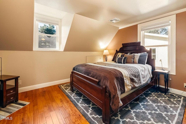 bedroom featuring lofted ceiling, visible vents, hardwood / wood-style floors, and baseboards