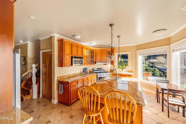 kitchen with a sink, appliances with stainless steel finishes, brown cabinetry, glass insert cabinets, and crown molding