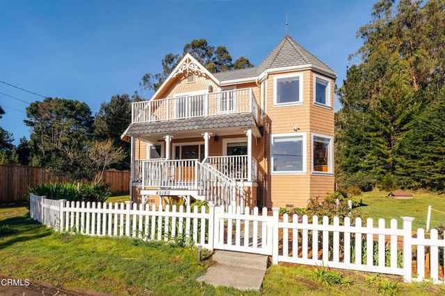 victorian-style house featuring a porch, a fenced front yard, a front yard, and a balcony