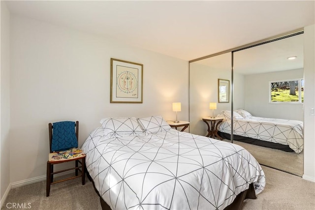 carpeted bedroom with a closet and baseboards