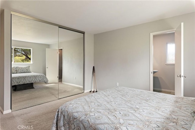 carpeted bedroom with a closet and baseboards