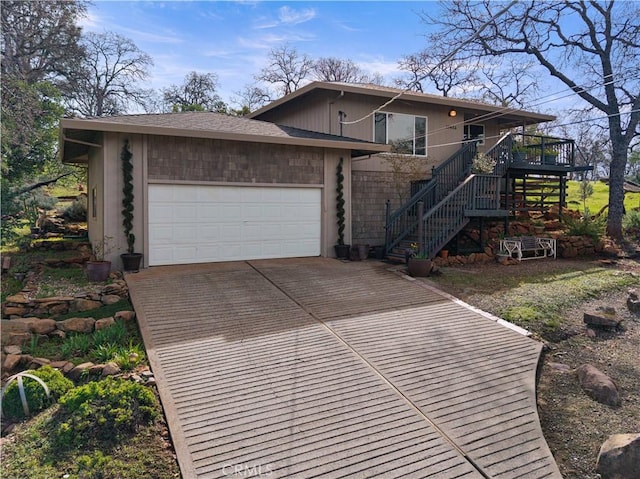 view of front facade featuring driveway, a garage, stairs, and a wooden deck