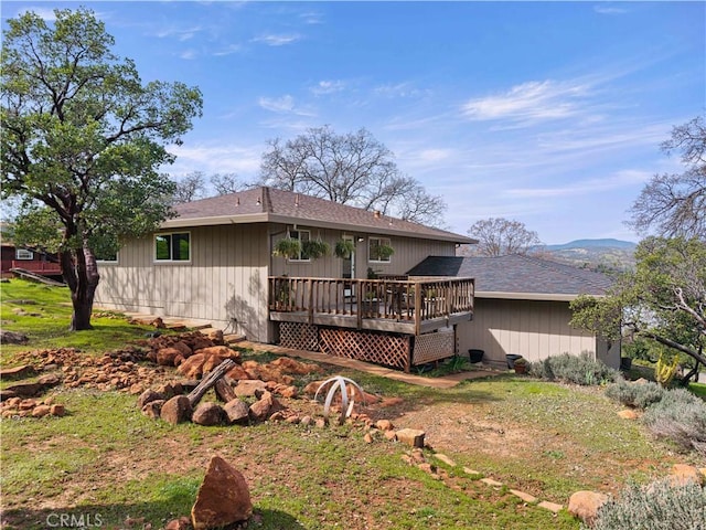 back of property with roof with shingles and a wooden deck