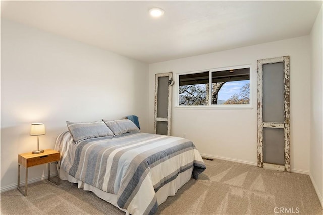 bedroom with baseboards and light colored carpet