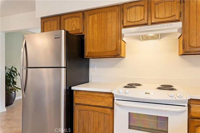 kitchen featuring brown cabinets, light countertops, electric range, freestanding refrigerator, and under cabinet range hood