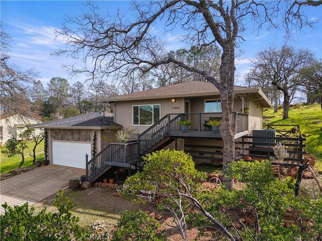 view of front of property featuring roof with shingles, stairway, an attached garage, central AC, and driveway