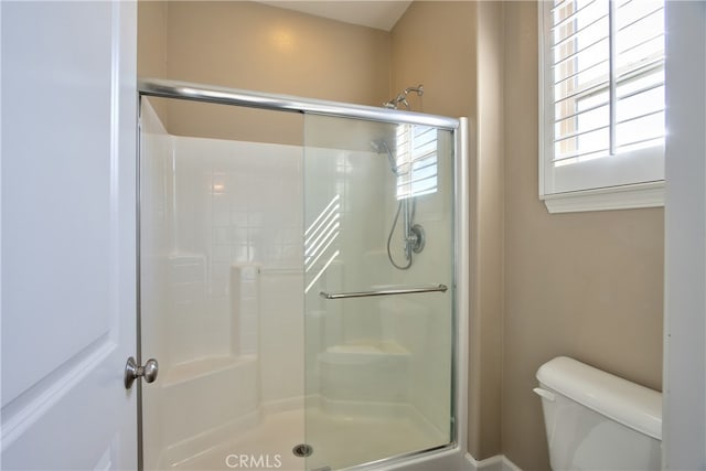 bathroom featuring a healthy amount of sunlight, a stall shower, and toilet