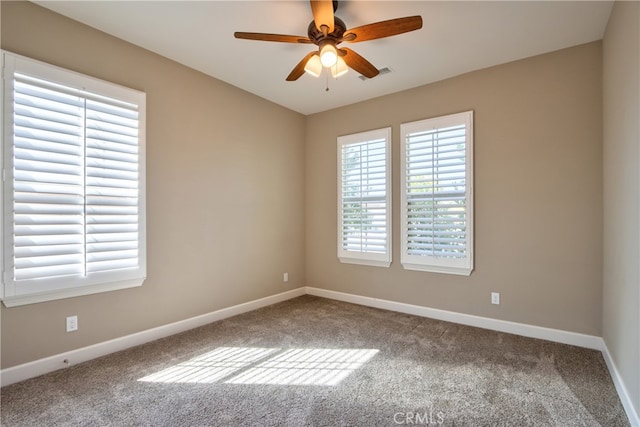 carpeted empty room featuring baseboards, visible vents, and a ceiling fan