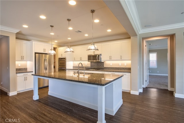 kitchen with a sink, an island with sink, stainless steel appliances, visible vents, and ornamental molding