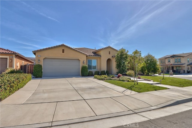 mediterranean / spanish house featuring a garage, a front lawn, stucco siding, a tiled roof, and driveway