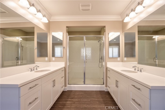 full bathroom featuring a stall shower, ornamental molding, a sink, and wood finished floors