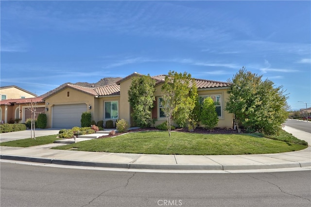 mediterranean / spanish house featuring a garage, stucco siding, driveway, and a front lawn