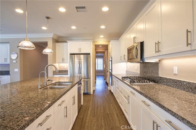 kitchen featuring visible vents, dark wood-type flooring, stainless steel appliances, crown molding, and a sink