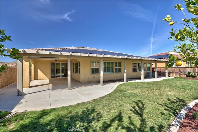 back of house featuring a patio, fence, a lawn, and stucco siding