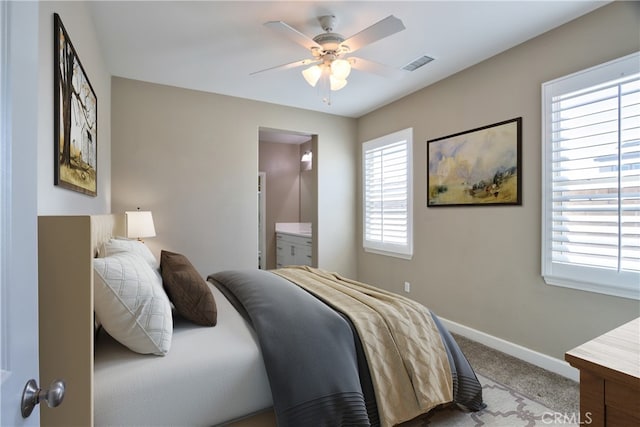 carpeted bedroom with baseboards, ceiling fan, ensuite bath, and visible vents