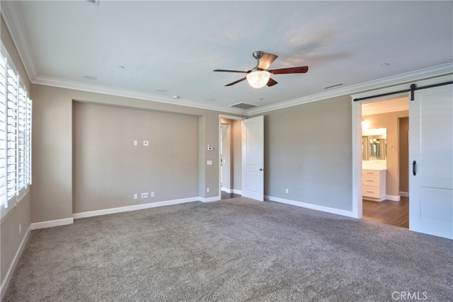 spare room with a barn door, visible vents, ceiling fan, ornamental molding, and carpet floors