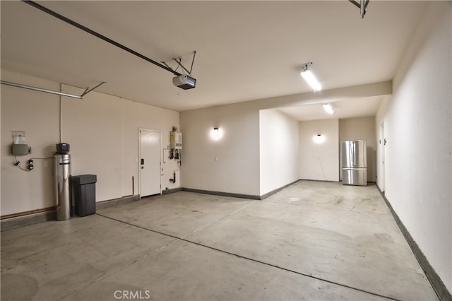 garage featuring baseboards, water heater, freestanding refrigerator, and a garage door opener