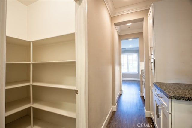 corridor featuring ornamental molding, dark wood finished floors, and baseboards