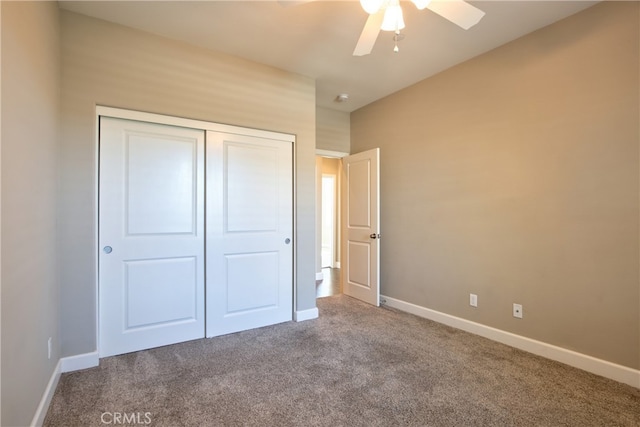 unfurnished bedroom with carpet floors, a closet, baseboards, and a ceiling fan